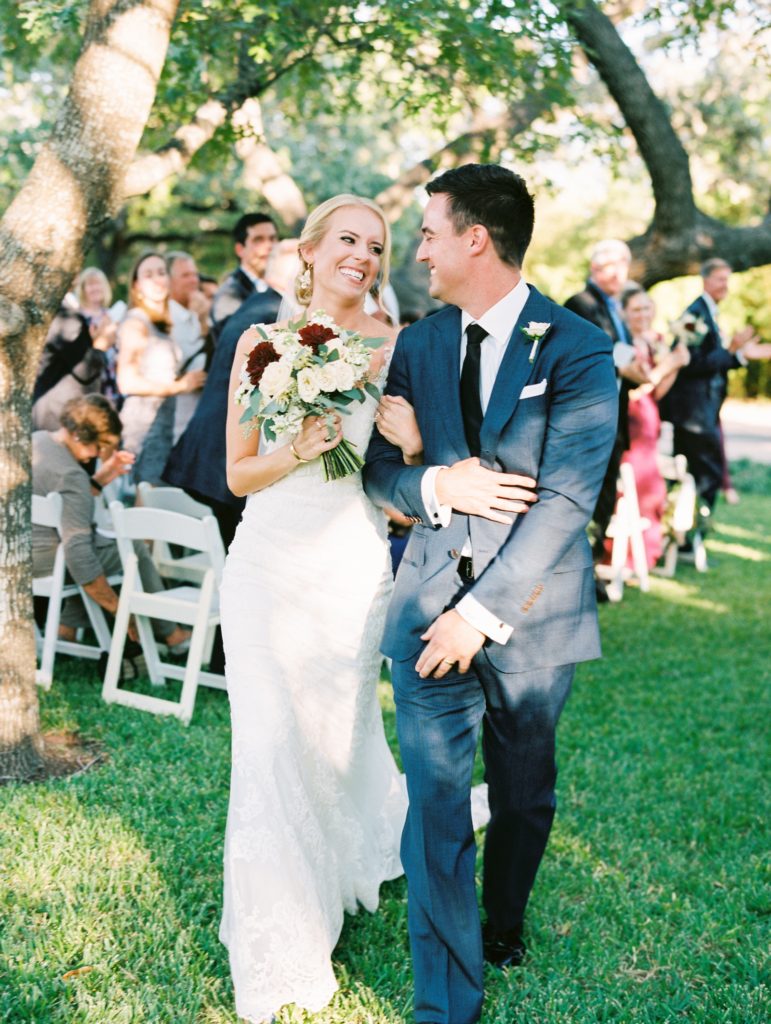 Film Fall wedding in Austin, Texas. Groom is wearing a navy suit, bride is wearing a lace wedding dress. Walking down the aisle as husband and wife.